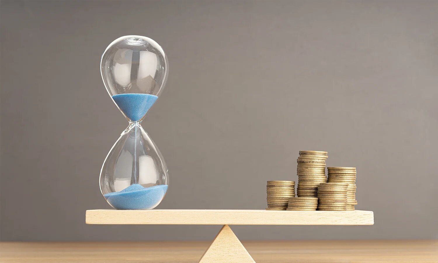 Balance avec sablier d'un côté et pièces de monnaie de l'autre côté